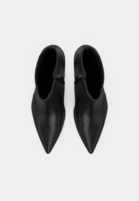 Pár čiernych kotníkových bot tvaru špičky so zipsami po bokoch, zobrazených zhora na jednoduchom bielom pozadí.