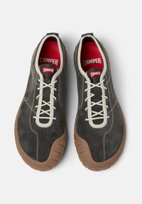 Γκρι σουέντ αθλητικά παπούτσια με μπεζ λαστιχένια σόλα· διαθέτουν λευκά κορδόνια, κόκκινη εσωτερική σόλα και αντίθετες ραφές. Σχεδιασμένα για άνεση και ευελιξία.