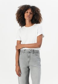 Hvit bomulls t-skjorte med rullede korte ermer, kombinert med høyhalsede, lysegrå jeans i denim med belte og subtil søm.