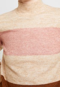 Stickad tröja med hög krage, i beige som basfärg och horisontella ränder i ljusrosa och mörkbrun. Mjuk textur, avkopplad passform.