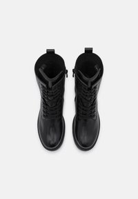 Botas negras de cuero hasta el tobillo con un acabado suave, que presentan cordones en la parte delantera y una cremallera lateral para facilitar su uso. Forro interior texturizado.