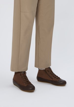 Sneaker alte marroni in suede e gomma, caratterizzate da un design con lacci, cerniere laterali e suola marrone a contrasto.