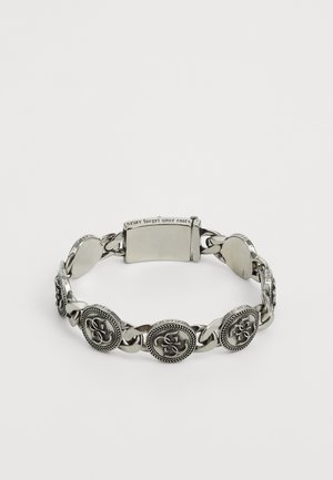 Bracelet en argent orné de médaillons circulaires avec des motifs complexes, chaîne entrelacée et fermoir gravé de "N'oubliez jamais vos racines."