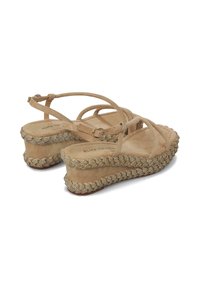 Sandalias de cuña de ante beige con tiras entrecruzadas, detalle tejido decorativo en la suela y una plataforma texturizada. Tacón plano.