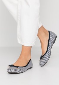 Ballettflats in Schwarz-Weiß-Streifen mit einer runden Zehenform, kontrastierendem schwarzen Besatz und kleinen Schleifendetails an der Vorderseite.