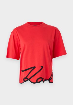 Rode katoenen T-shirt met korte mouwen, voorzien van een zwart cursief logo ontwerp langs de onderrand. Eenvoudige ronde halslijn.