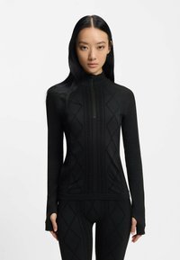 Czarny sportowy top z wysokim kołnierzem i zamkiem na ćwiartkę, z teksturowanymi diamentowymi wzorami z przodu i dopasowanymi rękawami.