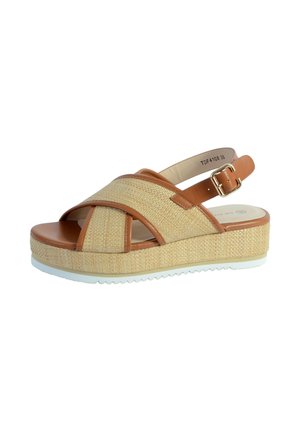 Sandalia de cuña con tiras cruzadas de tejido beige, ribete de cuero marrón, hebilla ajustable en el tobillo y suela de goma blanca.