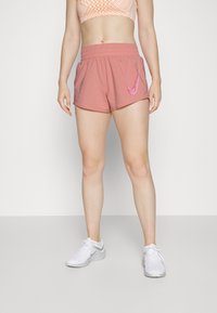 Pantalones cortos deportivos rosas con una cinturilla elástica, que presentan el logotipo de Nike Swoosh en blanco en el lado. Tejido suave, corte ajustado, longitud por encima de la rodilla.