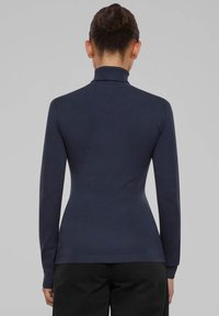 Pull col roulé bleu marine en tissu tricoté, avec manches longues et coupe ajustée, orné de détails côtelés au niveau du col et de l'ourlet.