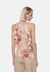 Blusa floreale in morbido tessuto rosa, con dettagli arricciati e zip sul retro. Il design presenta grandi fiori rosa e foglie verdi.