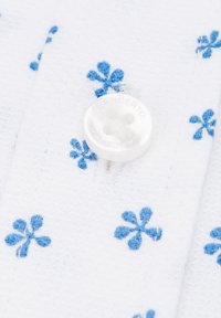 Biała tkanina z teksturowaną powierzchnią i rozproszonymi niebieskimi wzorami kwiatowymi. Przezroczysty guzik z napisem "LANCERTO" jest wyraźnie widoczny.