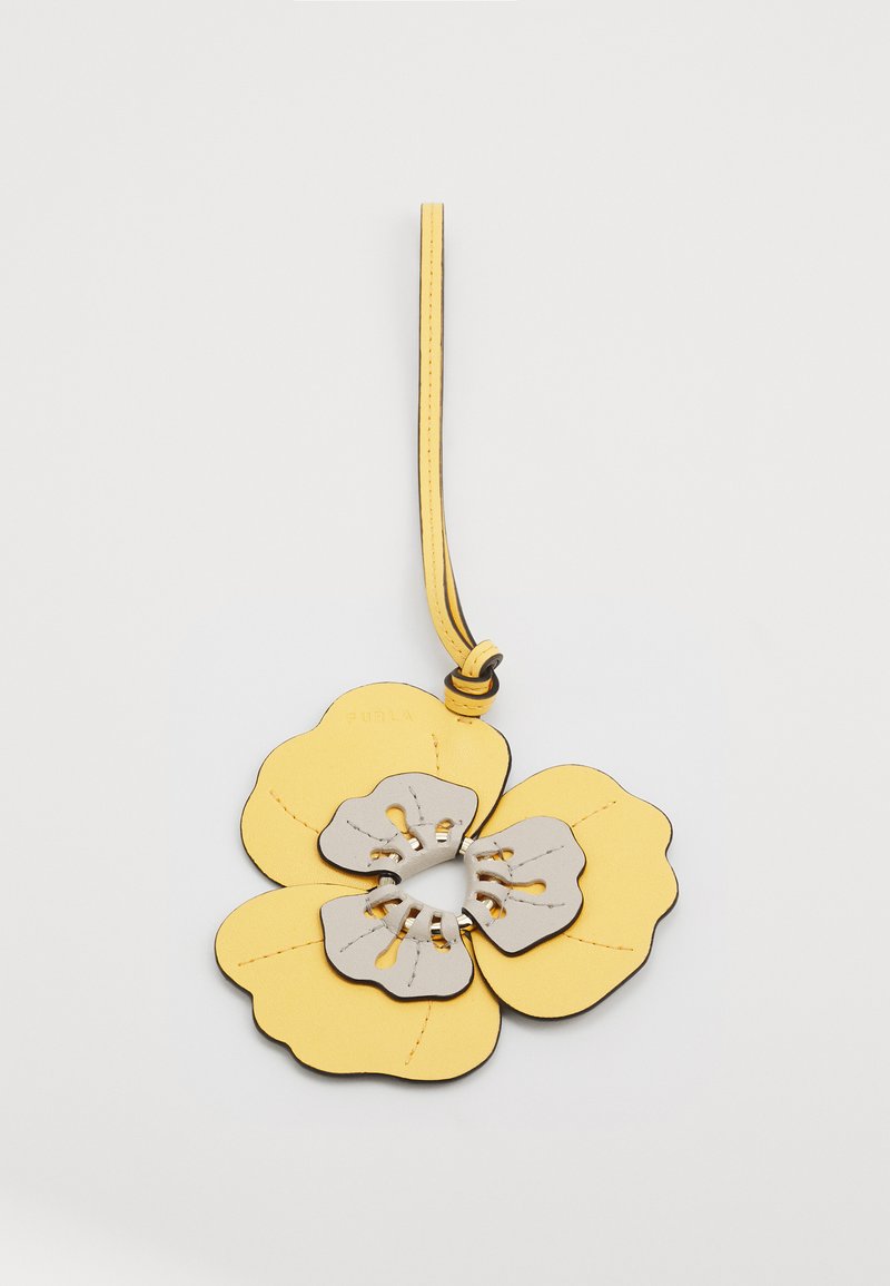 Accessoire en cuir jaune en forme de fleur avec des accents gris, couture détaillée, et une lanière pour l'accrocher. Design central avec découpe visible.