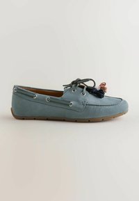 Mocassin en cuir bleu clair avec semelle marron, œillets latéraux, lacets foncés noués sur le dessus et pompons multicolores à l'avant.