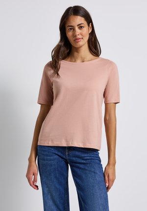 Top a maniche corte, rosa chiaro, in tessuto morbido con scollatura rotonda e vestibilità comoda, abbinato a jeans denim blu.