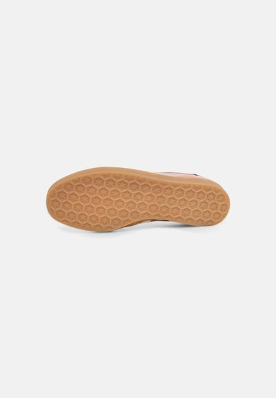 Semelle de chaussure en caoutchouc brun clair avec motif de bande de roulement texturé hexagonal et en forme d’étoile sur fond blanc.