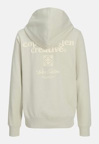 Hellgrauer Hoodie mit einer Kordelzugkapuze, versehen mit weißem, erhabenem Text "copenhagen creative" und "Studio Edition" auf der Rückseite. Weiche Textur.
