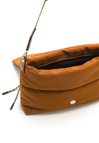 Borsa a mano in tessuto marrone con un design morbido e trapuntato, dotata di zip superiore, fodera interna nera e tracolla removibile.