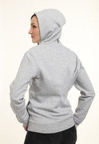 Sudadera con capucha gris hecha de una mezcla de algodón, con capucha redondeada, mangas largas, puños y dobladillo de canalé. Diseñada con un ajuste relajado.