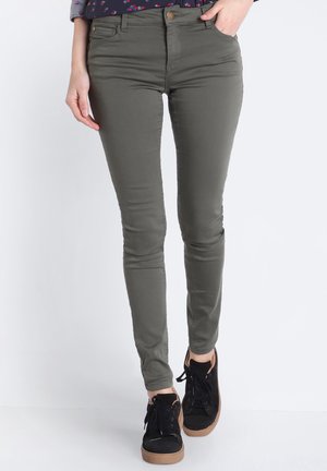 Jean skinny vert olive avec une coupe élégante, fermeture à bouton et poches avant. Associé à des baskets montantes noires avec une finition texturée.