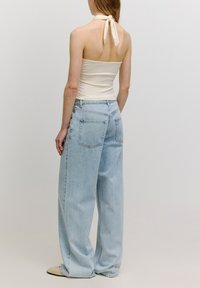 Lichtbeige haltertop gecombineerd met lichtblauwe high-waisted wijde jeans, met een achterzak en een comfortabele pasvorm.