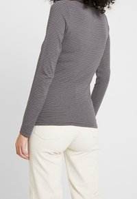 Långärmad grå och vit randig topp i mjukt tyg, med en figursydd design, rund hals och subtila detaljer på baksidan.