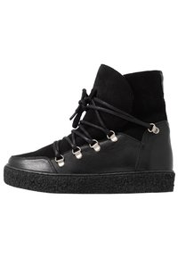 Zapatilla alta negra que combina cuero liso y gamuza, con ganchos de metal para los cordones, suela texturizada negra y diseño de punta redonda.