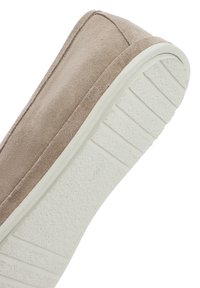 Zapato tipo slip-on de ante beige con una suela de goma blanca texturizada. La parte superior tiene un acabado suave y una puntera redondeada, con costuras visibles.