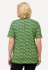 Top verde de manga corta con un patrón de diamantes en tonos de azul, verde y marrón. Tela suave con un ajuste relajado y cuello redondo.