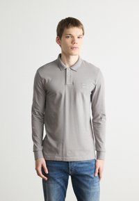 Long-sleeve grey polo shirt made of cotton, featuring a buttoned placket, ribbed collar, and a small branded patch on the chest.