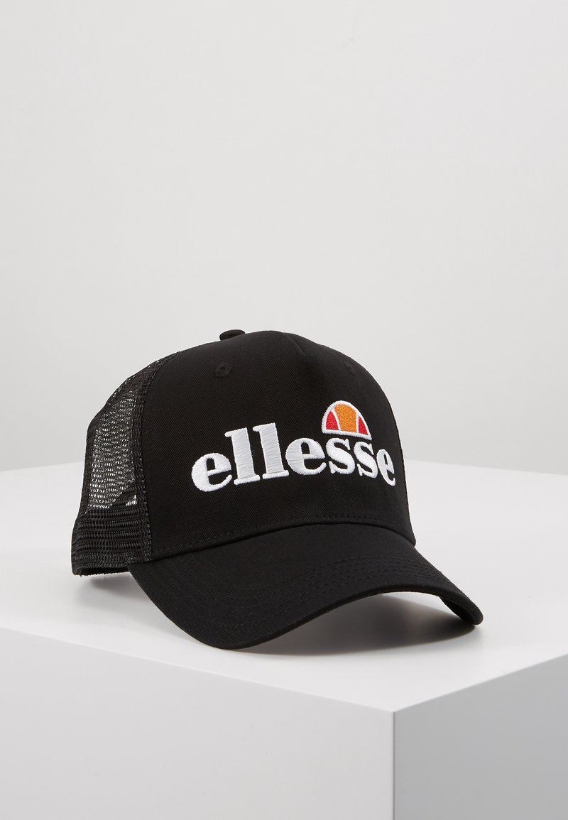 Casquette de baseball noire avec dos en mesh et logo blanc "ellesse" avec demi-cercle orange et rouge à l'avant, posée sur une surface blanche.