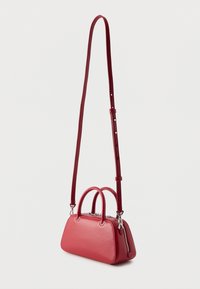 Μικρή κόκκινη δερμάτινη τσάντα χειρός με δύο κοντά χερούλια και μακρύ ρυθμιζόμενο ιμάντα ώμου, κλειστό με ασημένιο φερμουάρ.
