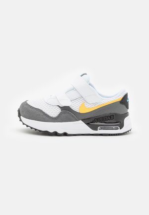 Sneaker bianca e grigia con tessuto in rete, fascette in Velcro e dettagli gialli. Presenta una suola AIRMAX nera con ammortizzazione ad aria visibile.