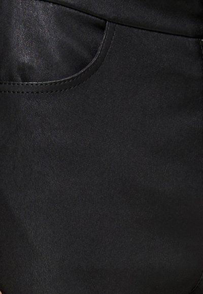 Tela de cuero sintético negro que muestra un primer plano de un bolsillo con una textura suave y un brillo sutil, con costuras curvadas a lo largo del borde.