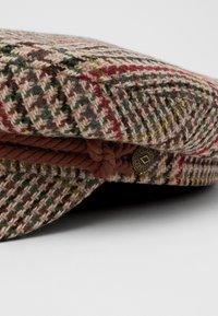 Ullflat cap med et flerfarget houndstooth-mønster, brunt tau-detalj, og en metallknapp på siden.