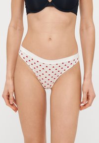 Valged bikiinialused väikeste punaste südame mustritega, elastse vöökoha ja minimaalse katvusega disainiga. Pehme puuvillane kangas, sileda tekstuuriga.