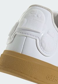 Bijele tenisice s teksturiranom površinom i potplatom od gume. Imaju utisnuti dizajn droida na peti. Minimalistički stil s čistim linijama.