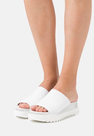 Sandales plateformes blanches à enfiler avec bout ouvert. Tige en cuir lisse, semelle blanche texturée et accents gris subtils au niveau du talon.