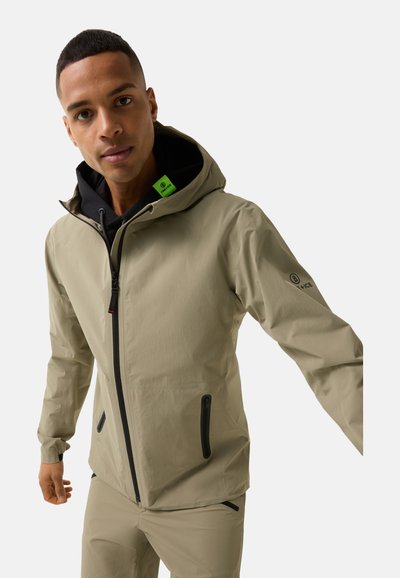 Beige waterproof jacket with a hood, black interior, front zipper, and two zippered side pockets; features a green label on the collar.