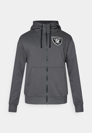 Šedá mikina na zip s přední kapsou, kapucí na šňůrku a logem Raiders na levé hrudi. Hladká látka s žebrovanými manžetami a lemem.