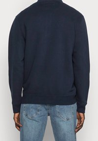 Navyblauwe sweatshirt met lange mouwen, ribgebreide manchetten en zoom. Glad geweven stof met een klassiek ronde hals ontwerp, achterkant zichtbaar.
