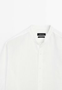 White long-sleeve shirt made of lightweight fabric. Features a mandarin collar, button front closure, and subtle textured weave.