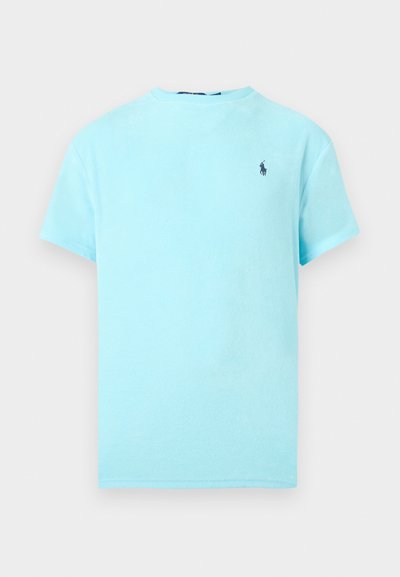 Ανοιχτό μπλε μπλουζάκι με κοντά μανίκια, με μικρό λογότυπο παίκτη πόλο σε σκούρο μπλε στο αριστερό στήθος, εμφανίζεται σε λευκό φόντο.