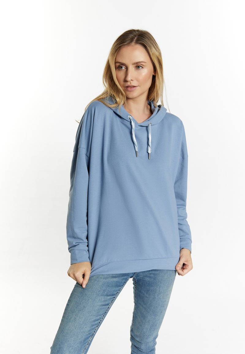 Felpa con cappuccio di colore azzurro, dal fit rilassato, con coulisse, maniche lunghe e una texture liscia. Indossata con jeans blu.