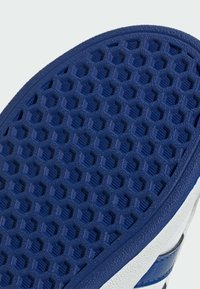 Blåt gummisåle til sko med sekskantet mønster og struktureret overflade, med hvide sideaccenter og en glat kant.