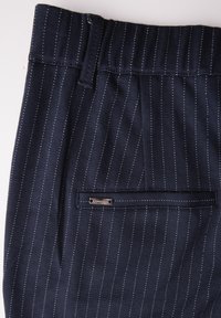 Marineblauwe gestreepte broek met een gestructureerde stof, tailleband en een achterzak met een klein metalen label voor merkaanduiding.