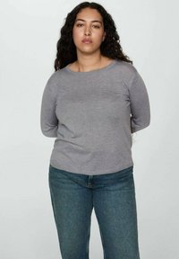 Siva dugih rukava majica s okruglim izrezom, mekanim teksturom i opuštenim krojem, uparen sa trapericama srednjeg pranja.