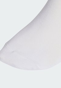 Biała bawełniana skarpeta o gładkiej fakturze, z wzmocnionym noskiem i ściągaczem w prążki. Zbliżenie na czubek skarpety.