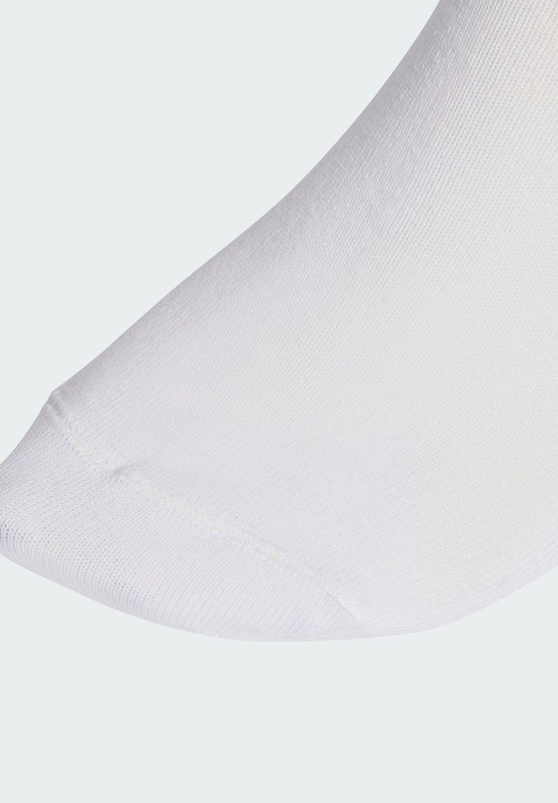 Vit bomullssocka med slät textur, utrustad med förstärkt tå och räfflad mudd. Närbild av sockans tå.