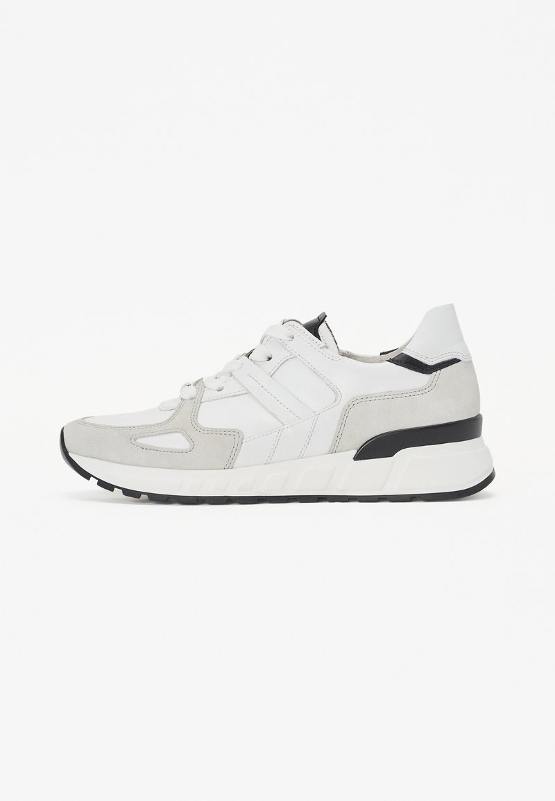 Sneakers med en blandning av vitt läder och ljusgrå mocka, med en kraftig svart sula och geometriska utskärningar för extra designdetaljer.